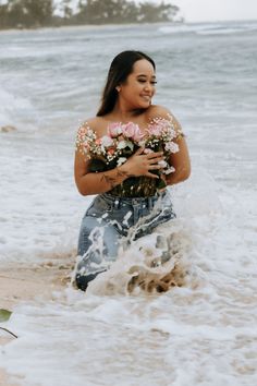 a woman walking into the ocean with flowers in her hands