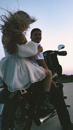 a man riding on the back of a motorcycle while holding a woman's hair