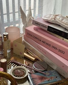 a table topped with lots of books next to a vase and candle holder on top of a window sill