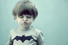 a little boy wearing a batman shirt making a funny face