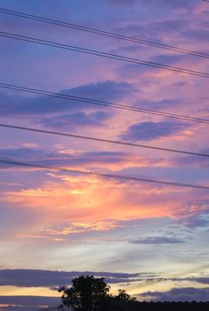 the sun is setting behind power lines and telephone poles