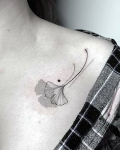 a woman's chest with a ginko leaf tattoo on the left side of her neck