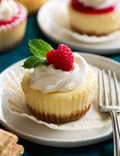 there is a small cupcake with whipped cream and raspberry on top, next to some crackers