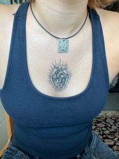 a woman wearing a blue tank top with a heart and sun tattoo on her chest