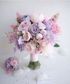 a bouquet of flowers sitting on top of a white table next to two small pieces of paper