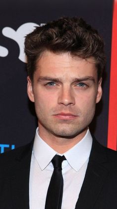 a close up of a person wearing a suit and tie with a serious look on his face