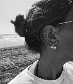 black and white photograph of woman with earring on the beach looking at the ocean