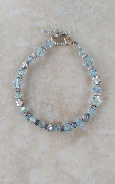 a blue bracelet with crystal beads and silver clasps on a marble counter top,