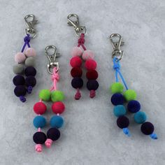 three key chains with pom - poms hanging from them on a white surface