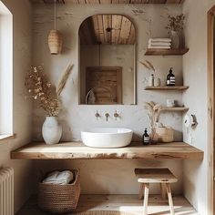 a white sink sitting under a bathroom mirror next to a wooden shelf filled with towels