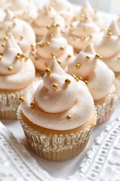 cupcakes with white frosting and gold sprinkles on a plate