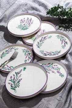 four plates with purple and green designs on them, one has a fork in the middle