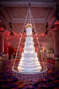 a large white wedding cake sitting on top of a table in front of a chandelier