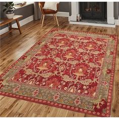 a red rug with an ornate design on the floor in front of a fire place