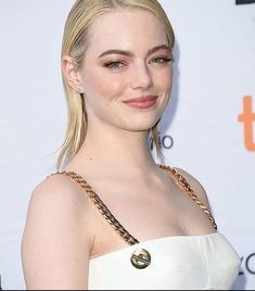 a woman with blonde hair wearing a white strapless dress and gold chain around her neck