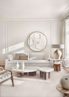 a living room filled with furniture and a large round mirror on the wall above it