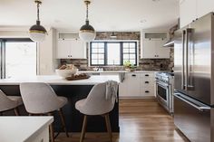 a modern kitchen with white cabinets and stainless steel appliances, along with wooden flooring