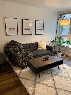 a living room with a couch, coffee table and pictures on the wall above it