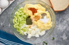 an image of eggs, onions and seasoning in a bowl with bread on the side