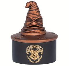 a harry potters hat on top of a black and gold container with the hogwart's crest