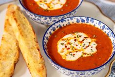 two bowls of soup with bread sticks on the side