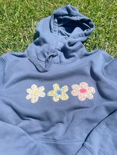 a blue hoodie with flowers on it laying in the grass