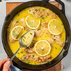 a pan filled with chicken and lemons on top of a wooden table