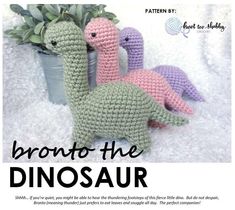 three crocheted dinosaurs sitting next to each other in front of a potted plant