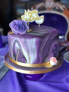 a purple and gold birthday cake sitting on top of a table