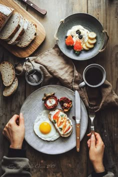 an overhead view of eggs, toast and fruit on a plate with two hands holding a knife