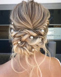 a woman with blonde hair and pearls in her hair is seen from the back, wearing a