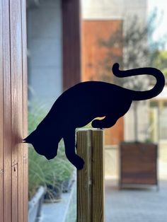 a black cat silhouetted on the side of a wooden post