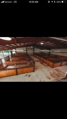 the inside of an empty building with lots of wooden stalls and railings on each side