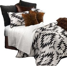 a bed with black and white comforter, pillows and blankets on it's sides