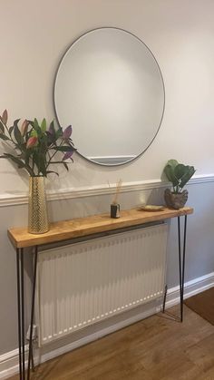 a vase with flowers on top of a table next to a mirror and radiator