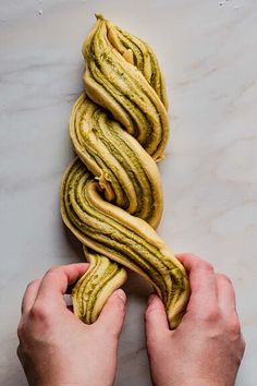 a person holding some kind of food in their hands on a table with marble counter top