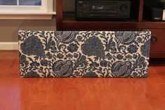 a blue and white floral print purse sitting on top of a hard wood floor next to a radio