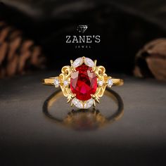 a ring with a red stone surrounded by white and yellow diamonds on a black surface