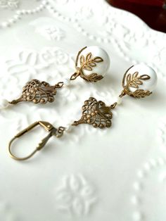 White Large Filigree and Leaf Brass Drop Dangle Long Earrings Large white glass beads with a vintage leaf cap and vintage filigree finding dangle from antiqued brass lever back ear wires. They may be changed to French hook ear wires or post style earrings. See last picture for reference. You will be prompted to select your preference when you add them to your cart. They measure 2 7/8 inches from top of lever back style wire. 👑 More Dangle Earrings: https://www.etsy.com/shop/tinygoldcrowns?ref=s Vintage Dangle Earrings, Manga Jewelry, Long Dangle Earrings, Large Earrings, Style Earrings, Jewelry Diy, Large White, Long Earrings, White Glass