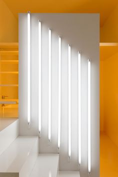 an empty room with some white lights on the wall and stairs leading up to it