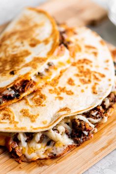 two quesadillas stacked on top of each other with cheese and meat toppings