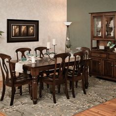 a dinning room table with chairs and a china cabinet in the corner, along with a rug on the floor