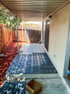 an outdoor patio with blue tiles on the ground and a box in front of it