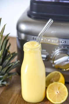 a pineapple smoothie in a mason jar next to sliced lemons