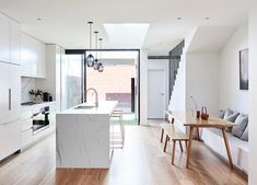 an open kitchen and living room with white walls, wood flooring and modern appliances