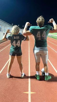 two people standing on a track with their arms in the air