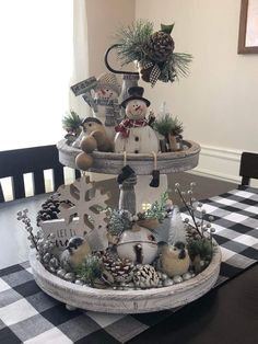 a christmas tree with snowmen, pine cones and ornaments in it on a black and white checkered tablecloth