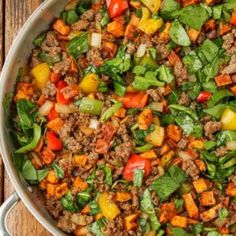 a pan filled with meat and vegetables on top of a wooden table