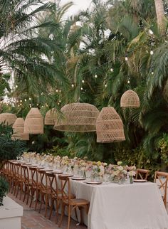 a long table is set up for an outdoor wedding reception with hanging birdcages