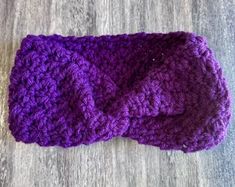 a purple crocheted headband laying on top of a wooden floor